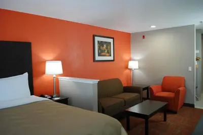 a hotel room with a bed and a couch and a chair at Quality Inn & Suites Fresno Northwest in Fresno