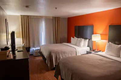 a hotel room with two beds and an orange wall at Quality Inn & Suites Fresno Northwest in Fresno