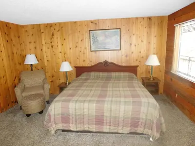 a bedroom with a bed and a chair and two lamps at The Tamarack Lodge in Lakeshore