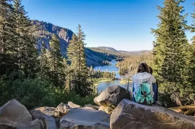 a woman sitting on a rock overlooking a lake at The Bridges 102 in Mammoth Lakes