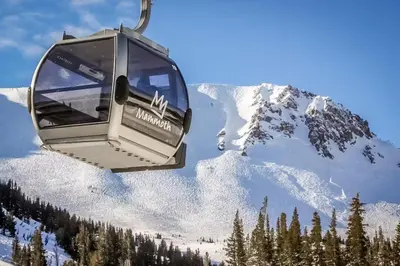 a ski lift with a snow covered mountain in the background at The Bridges 102 in Mammoth Lakes