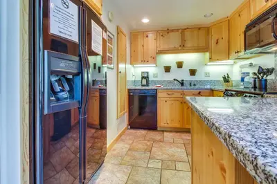 a kitchen with wooden cabinets and a refrigerator at Val D'Isere 45 in Mammoth Lakes