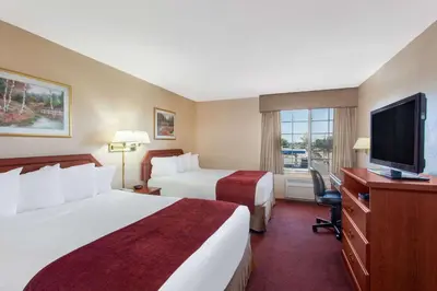 a hotel room with two beds and a flat screen tv at Ramada by Wyndham Fresno Northwest in Fresno