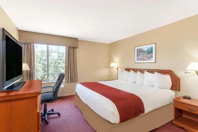 a hotel room with a bed and a desk and a television at Ramada by Wyndham Fresno Northwest in Fresno