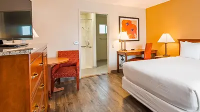 a hotel room with a bed and a desk with a television at Best Western Golden Key in Auburn