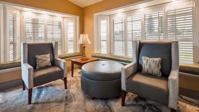 two chairs and a ottoman in a room with windows at Best Western Golden Key in Auburn