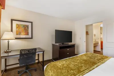 a hotel room with a bed and a desk and a television at Best Western Luxury Inn in Tracy