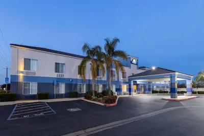 a hotel with palm trees in a parking lot at Days Inn by Wyndham Lathrop in Lathrop