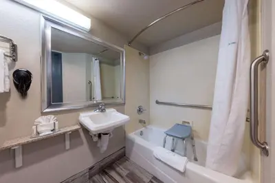 a bathroom with a sink and a mirror and a bath tub at Comfort Inn Lathrop Stockton Airport in Lathrop