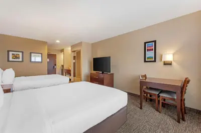 a hotel room with two beds and a desk and a television at Comfort Inn Lathrop Stockton Airport in Lathrop