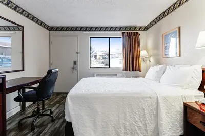 a hotel room with a bed and a desk and a window at Knights Inn Madera in Madera