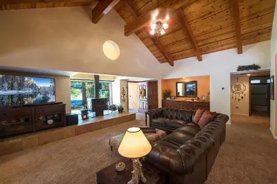 a living room with a leather couch and a flat screen tv at Bruin's Den in Wawona