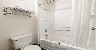 a white bathroom with a toilet and a shower at Budget Inn and Suites Stockton Yosemite in Stockton