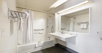 a white bathroom with a sink and a mirror at Budget Inn and Suites Stockton Yosemite in Stockton