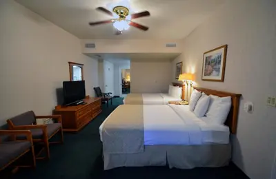 a hotel room with two beds and a ceiling fan at Garden Inn and Suites Fresno in Fresno