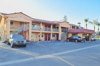 a hotel with cars parked in a parking lot at Super 8 by Wyndham Visalia in Visalia