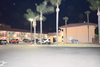 a parking lot with palm trees in front of a motel at Super 8 by Wyndham Visalia in Visalia
