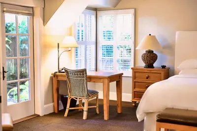 a bedroom with a desk and a bed and windows at Appellation Lodi - Wine & Roses Resort and Spa in Lodi