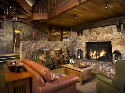 a living room with a stone fireplace and leather furniture at Mammoth Mountain Inn in Mammoth Lakes