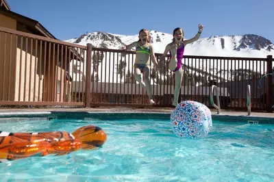 two girls are standing next to a swimming pool at Mammoth Mountain Inn in Mammoth Lakes