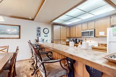 a large kitchen with a long counter and chairs at Mountainback 47 in Mammoth Lakes