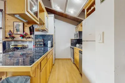 a kitchen with wooden cabinets and a white refrigerator at Saddle Road Condo in Bijou Park