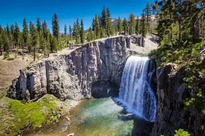 a waterfall on the side of a mountain with trees at The Summit 206 in Old Mammoth