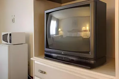 a television sitting on top of a dresser with a bed at Days Inn by Wyndham Gilroy in Gilroy