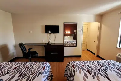 a hotel room with a bed and a desk with a mirror at California Inn and Suites, Rancho Cordova in Rancho Cordova