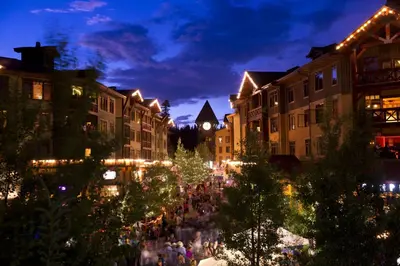 a crowd of people walking through a city at night at The Village Lodge in Mammoth Lakes