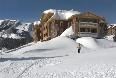 a person standing in the snow in front of a house at Juniper Springs Resort in Mammoth Lakes