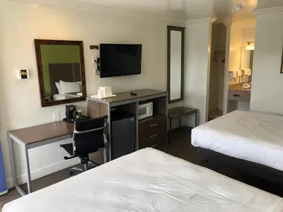a hotel room with a bed and a desk with a television at Gilroy Inn in Gilroy