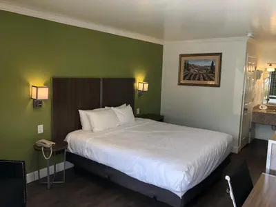 a bedroom with a large white bed with green walls at Gilroy Inn in Gilroy