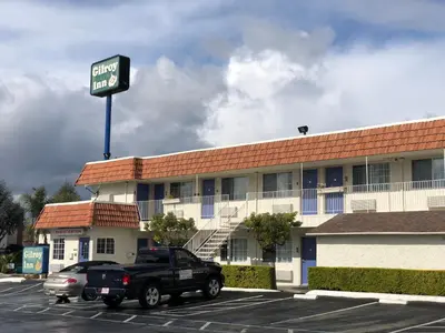 a black truck parked in a parking lot in front of a hotel at Gilroy Inn in Gilroy