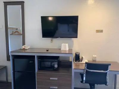 a desk with a television on a wall with a chair at Gilroy Inn in Gilroy