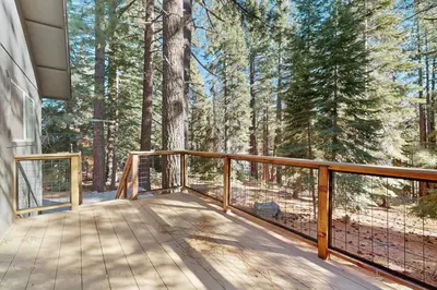 a wooden balcony with a view of a forest at Lazy Bear Retreat in Mevers