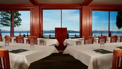a restaurant with white tables and chairs and windows at Sunnyside Resort and Lodge in Tahoe City