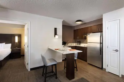 a kitchen with a bed and a kitchen with a table and a refrigerator at Sonesta ES Suites Fresno in Fresno