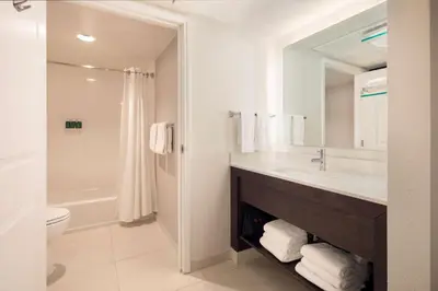 a bathroom with a sink and a toilet and a mirror at Sonesta ES Suites Fresno in Fresno