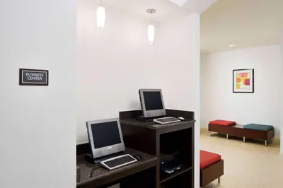 a room with two computers on a desk with a bed at Sonesta ES Suites Fresno in Fresno