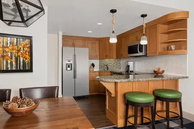 a kitchen with a refrigerator and a table with stools at Marriott Grand Residence Club, Lake Tahoe in South Lake Tahoe