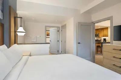 a bedroom with a white bed and a kitchen at Marriott's Timber Lodge in South Lake Tahoe