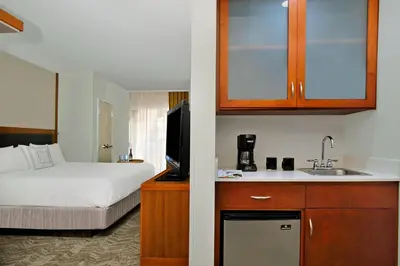 a hotel room with a bed and a kitchen with a sink at SpringHill Suites by Marriott Madera in Madera