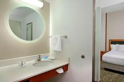 a bathroom with a sink and a mirror and a bed at SpringHill Suites by Marriott Madera in Madera