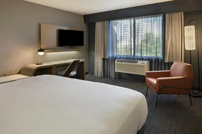 a hotel room with a bed and a chair and a window at Courtyard by Marriott Sacramento Midtown in Sacramento