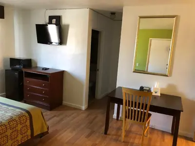 a bedroom with a desk and a bed and a mirror at Americas Best Value Inn Visalia in Visalia