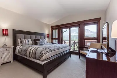 a bedroom with a bed and a balcony with mountains at Juniper Crest 3 in Old Mammoth