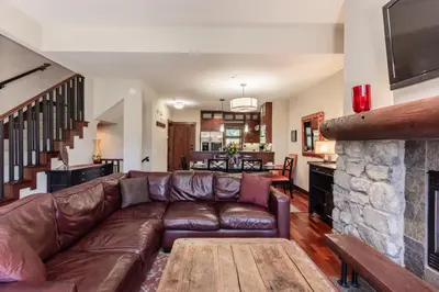 a living room with a leather couch and a stone fireplace at Juniper Crest 3 in Old Mammoth
