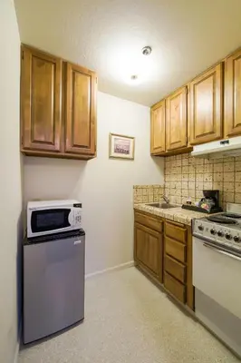 a small kitchen with wooden cabinets and a microwave at Historic Cary House Hotel in Placerville