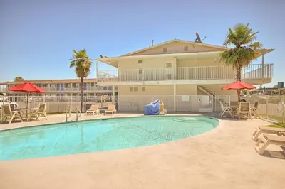 a swimming pool with chairs and umbrellas in front of a building at Motel 6-Fresno, CA - Blackstone North in Fresno